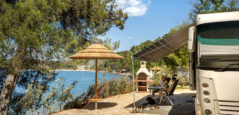 Paar campt mit Wohnmobil direkt am Meer im Lanterna Premium Camping Resort