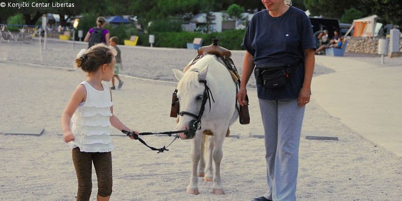 Mädchen hält die Zügel von Pony am Strand beim Ausflug mit Reitzentrum Libertas