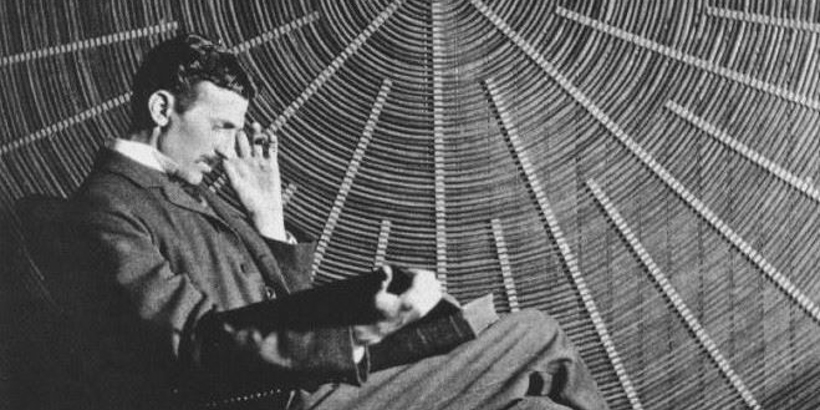 Nikola Tesla, with Rudjer Boscovich's book Theoria Philosophiae Naturalis, in front of the spiral coil of his high-voltage Tesla coil transformer